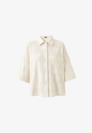 Cremefarbenes Hemd zum Zumknöpfen mit weiten dreiviertel Ärmeln, einer Brusttasche und einem dezenten, floralen Präge-Muster.