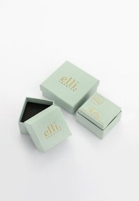 Hexagonala mintgröna smyckeskrin med guldtryck; ett är öppet och avslöjar en svart inredning. Liten och elegant design, lämplig för presenter.