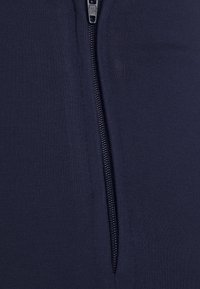 Tecido azul-marinho com uma textura fina, apresentando um fecho lateral com zipper, destacando um acabamento suave e um design minimalista.