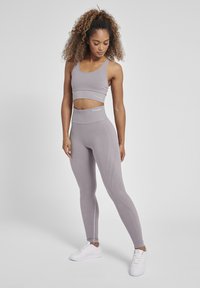 Lichtgrijs geribbeld trainingsset bestaande uit een cropped tanktop en hoge taille leggings met textuuraccenten en reflecterend logo.