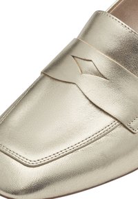 Metalliska guldloafers med en slät läderfinish, med ett brett band över framtill och subtil präglad detaljering.