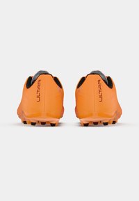 Oranžové sportovní boty s texturovaným svrškem, černými akcenty a výraznou podešví s viditelnými hroty. Na patě je nápis "ULTRA".