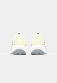 Chaussures de sport vert lime et noires avec tige en maille, semelle intermédiaire blanche épaisse et semelle extérieure en caoutchouc gris texturé. La vue arrière met en évidence le design du talon.