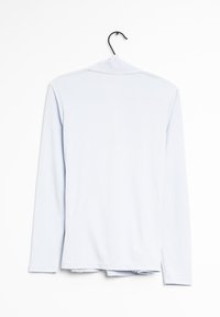 Vaaleansininen pitkähihaisinen paita, joka on valmistettu pehmeästä kankaasta. Paidassa on yksinkertainen muotoilu, pyöreä kaula-aukko ja suora helma. Paita on ripustettu mustalle koukulle.