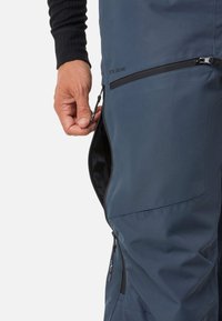 Wasserabweisende dunkelblaue Hosen mit einer seitlichen Zipper-Tasche, die eine glatte Textur und verstärkte Nähte für Langlebigkeit bieten.