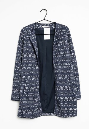 Marineblauwe en witte lange cardigan met patroon, open voorkant, twee zijzakken, hangend aan een zwarte hanger tegen een witte achtergrond.