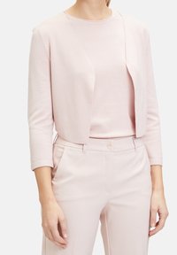 Světlá růžová kardigan s tříčtvrtečními rukávy, otevřený přední design, spojený s odpovídajícím světle růžovým topem a přizpůsobenými kalhotami. Hladká textura.