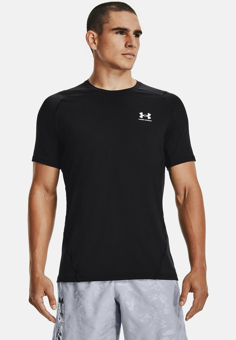 Camiseta atlética negra de manga corta hecha de material sintético, con un escote redondo y un pequeño logo blanco en el pecho.