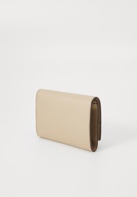 Le portefeuille en cuir beige présente un design simple avec une forme rectangulaire, une texture lisse et des coutures visibles le long des bords.