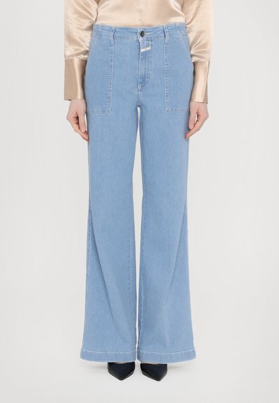 Lyseblå denim wide-leg jeans med høj talje, to forlommer og rå kantfinish, parret med spidse sorte hæle.
