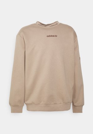 Sudadera beige de algodón, con mangas largas, cuello redondo y un pequeño logo tonal en el pecho. Textura suave, ajuste relajado.