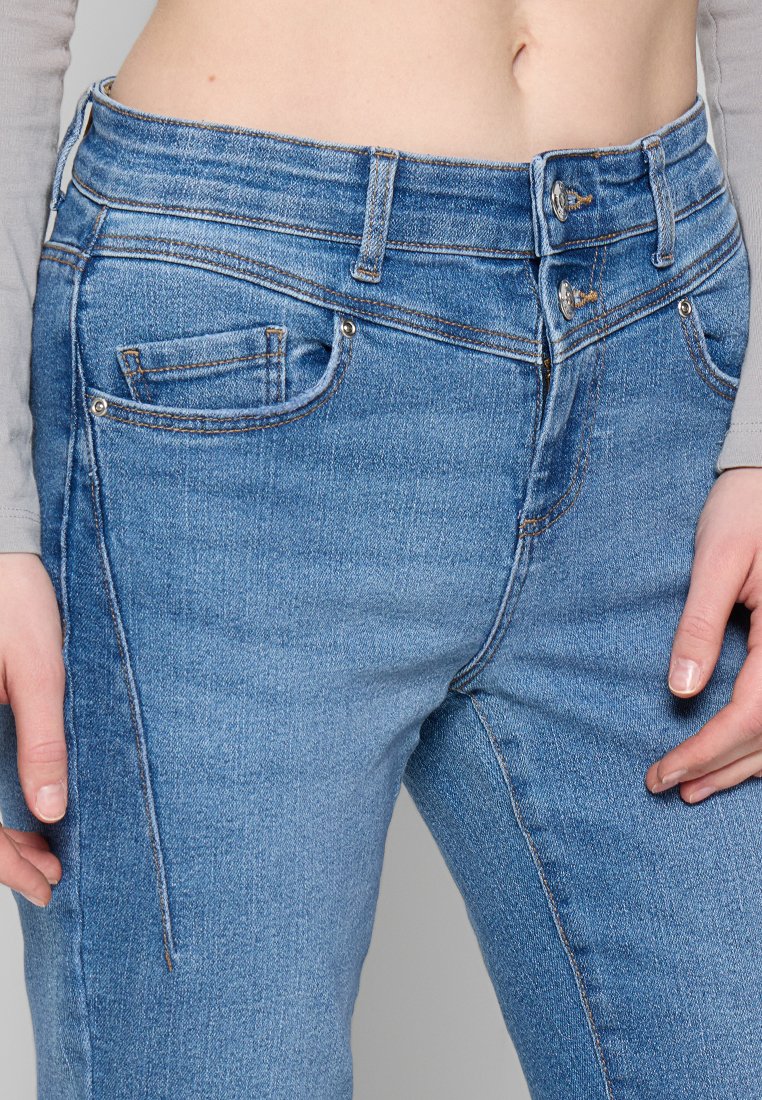 Hellblaue Denim-Jeans mit einem hoch geschnittenen Design, ausgestattet mit zwei Knöpfen, Fronttaschen und subtilen Nähten. Glatte Textur.