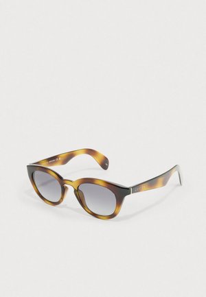 Óculos de sol tartaruga com formato de olho de gato, lentes cinza degradê e a marca "GUCCI" em ouro nas hastes. Material de acetato suave.