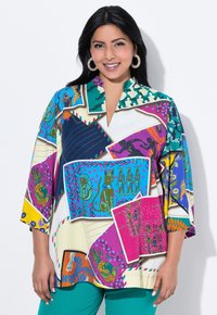 Bunte, gemusterte Bluse mit einer Mischung aus Designs in Lila, Blau, Grün und Gelb. Sie hat einen V-Ausschnitt und Dreiviertelärmel.