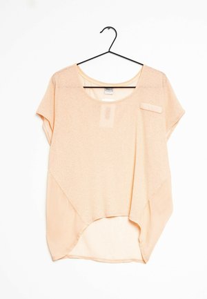 Lyserød ferskenfarvet kortærmet top med rundet halsudskæring, detaljer i gennemsigtigt stof og en høj-lav kant. Har en lille lomme foran.