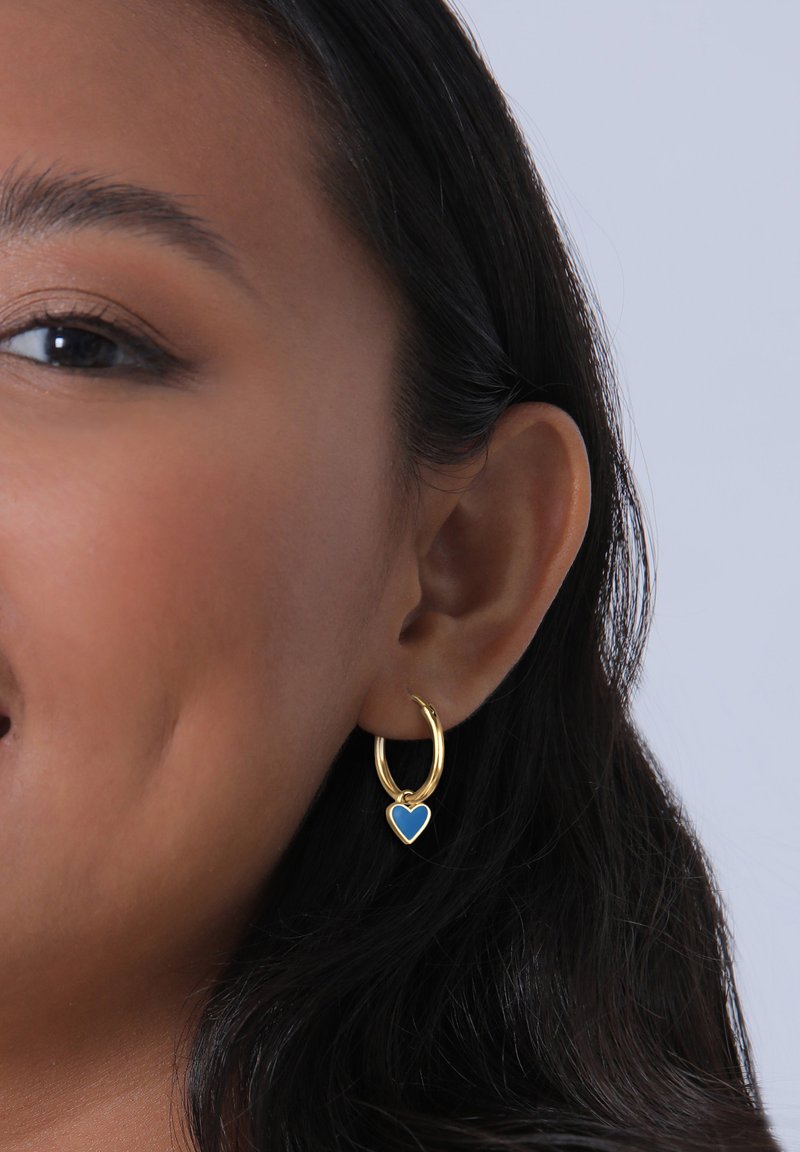Guld hoops örhänge med en liten blå hjärta charm. Örhänget har en polerad yta och en enkel, elegant design.