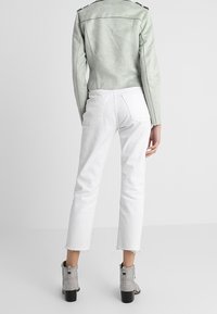 Grön faux-suede jacka, vita cropped-jeans, grå ankelstövlar med silverdekorationer och robusta svarta klackar.