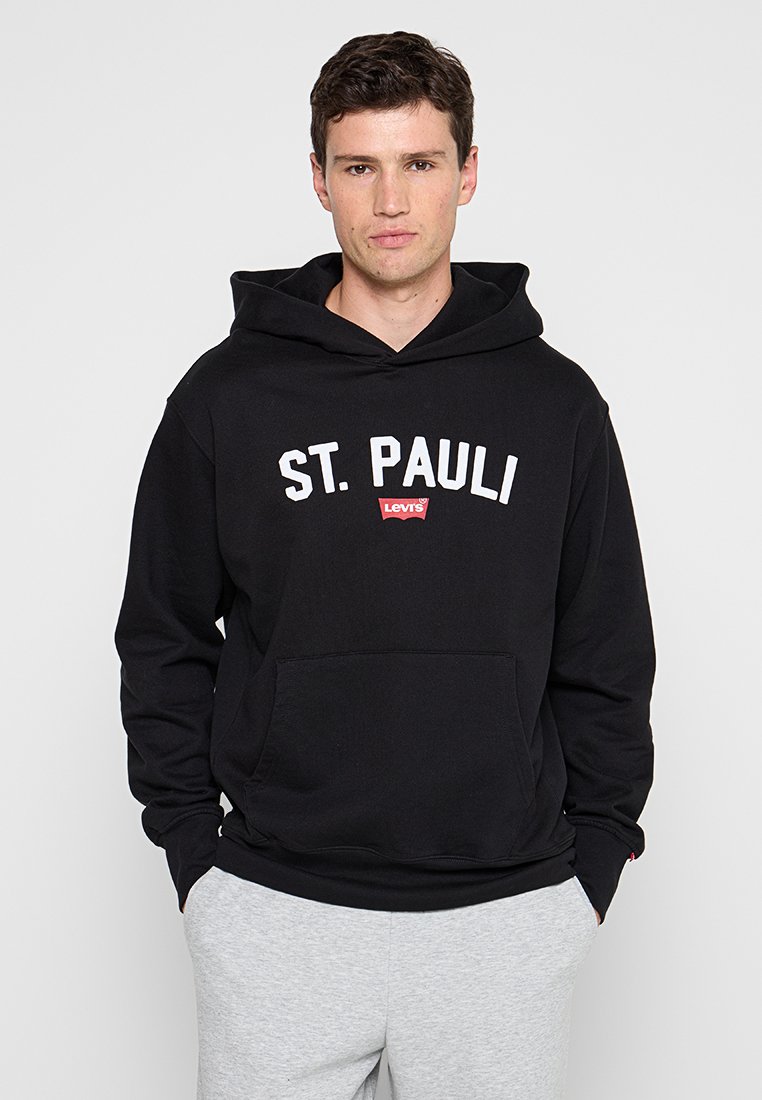 Schwarzer Hoodie mit dem Text "ST. PAULI" in Weiß und einem roten Levi's-Logo, mit einer Fronttasche und entspannter Passform. Geschmeidige Stoffstruktur.