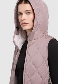 Helles rosa, gesteppte Weste mit Kapuze, ausgestattet mit einem Frontreißverschluss und schwarzen Akzenten. Das Material wirkt glatt mit einem leichten Glanz.