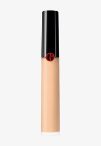 Base líquida en un tubo de vidrio transparente, tono beige claro, con un tapón negro que presenta un logotipo rojo circular. Diseño suave y elegante.