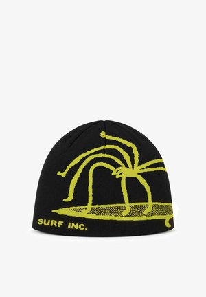 Czarna czapka typu beanie z żółtym, przypominającym pająka wzorem, stojąca na desce surfingowej, z tekstem "SURF INC." w lewym dolnym rogu.