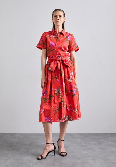 Red floral shirt dress with short sleeves, cinched waist, and tie belt. Features various colorful flower patterns on a smooth fabric.
