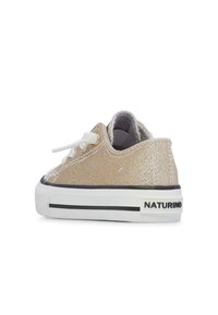 Zapatillas de lona doradas brillantes con cordones blancos, forro gris, detalles negros y una suela blanca que presenta una franja negra y el logo de la marca.