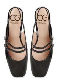 Tacones slingback de charol negro con dos correas ajustables. Presentan una punta cuadrada y un forro interior suave. Logo dorado en el interior.