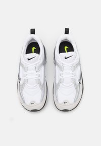 Biele športové topánky s šedými a čiernymi akcentmi, s priehľadnou vrchnou časťou, polstrovanou podrážkou a výrazným logom Nike v čiernej a zelenej farbe.