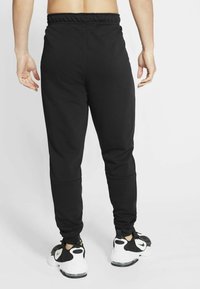 Zwarte sportieve joggingbroeken met een elastische tailleband, afgeslankte pasvorm en enkelmanchetten. Draag ze met zwart-witte sneakers. Soepele stofstructuur.