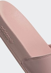 Różowe klapki z gładką syntetyczną cholewką i teksturowaną gumową podeszwą. Posiadają wytłoczone logo oraz starannie wykonane szwy.