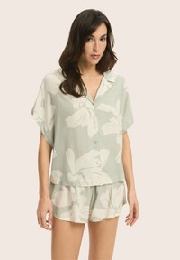 Jasnozielona, kwiatowa bluzka z krótkim rękawem, z kołnierzykiem, zapinana na guziki, oraz dopasowane szorty. Miękka tkanina z dużymi wzorami kwiatowymi.