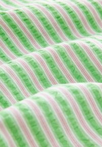 Grüner Stoff mit abwechselnd dünnen weißen und rosa Streifen, der eine strukturierte Optik aufweist und aus einem weichen, leichten Material besteht.