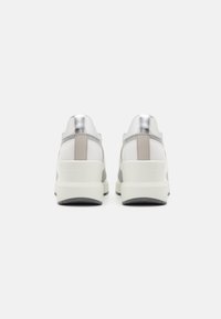 Basket blanche et argentée au design épuré, présentant un dos texturé, des accents gris et une semelle blanche épaisse.