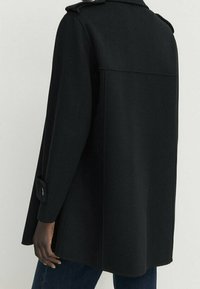 Czarny płaszcz z mieszanki wełny o prostej sylwetce, z wysokim kołnierzem, mankietami zapinanymi na guziki i minimalistycznym designem.