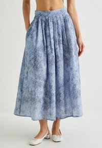 Maxi-Rock mit blauem Muster und Falten, aus leichtem Stoff gefertigt. Verfügt über eine hohe Taille und Seitentaschen. Mit subtiler Stickerei verziert.