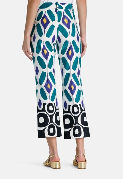 Pantaloni evazați dintr-un material alb, cu un model îndrăzneț de forme turcoaz, mov și galbene. Dantelul se termină cu cercuri negre contrastante.