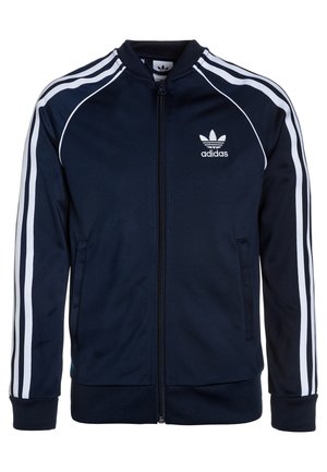 Námořnická modrá sportovní bunda Adidas se třemi bílými pruhy. Má zapínání na zip, žebrované manžety a vyšitý logo na hrudi.