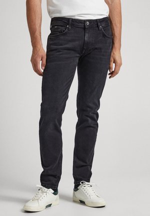 Zwarte denim jeans met een slim fit, vijf zakken, subtiele slijtage. Gekomponieerd met witte sneakers met groene accenten.