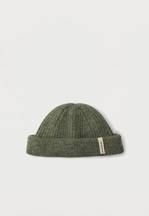 Bonnet en tricot côtelé vert avec un revers retourné. Présente une petite étiquette rectangulaire sur le côté. Texture douce et forme arrondie.