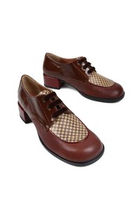 Brązowe skórzane buty z błyszczącym wykończeniem i tkaniną w wzór hounds-tooth na czubku, z niskim czerwonym obcasem i sznurowanym fasonem.