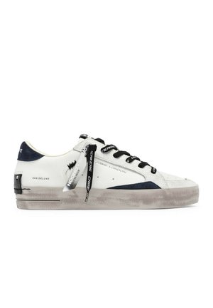Sneaker low-top bianco e grigio con lacci neri, etichette brandizzate nere e bianche e dettagli in camoscio nero su suola e tallone.