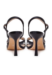 Sandales à talons hauts en cuir noir avec une lanière de cheville, bout ouvert et plusieurs lanières croisées. Caractéristiques d'un talon aiguille et d'une semelle nude.