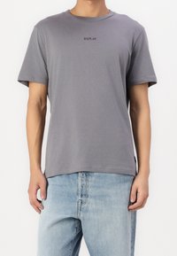 Grijze katoenen T-shirt met ronde hals en korte mouwen; heeft een minimalistisch zwart "REPLAY" logo op de borst.