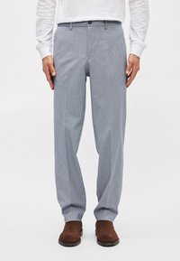 Ανοιχτόγκρι παντελόνι καρό με ίσια γραμμή, διαθέτει κλείσιμο με κουμπί και πλαϊνές τσέπες, συνδυασμένο με καφέ σουέτ παπούτσια.