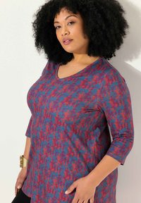 V-hals top van multicolore stof met een abstract patroon in rood, blauw en paars. Lange mouwen en een relaxed fit met zijnaad.