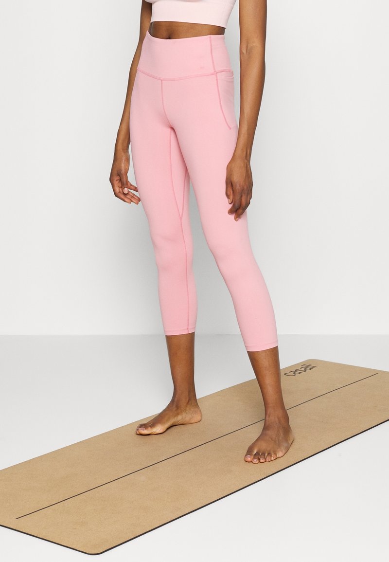 Rosa capri leggings med hög midja och sidfickor, med en slät, töjbar textur och kontrasterande sömmar.