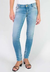 Jean skinny bleu clair en denim, avec un design classique à cinq poches et des boutons en laiton. Texture lisse, finition délavée moyenne.