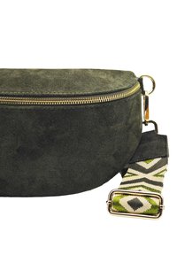 Sac en daim vert à forme arrondie, avec une fermeture éclair dorée et une sangle en tissu à motifs aux accents verts et blancs.