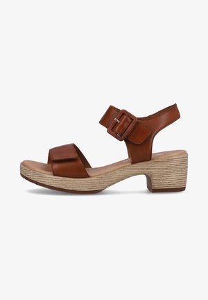 Brown leather sandal with a rounded toe, ankle strap, and a buckled closure. Features a textured beige block heel and platform.